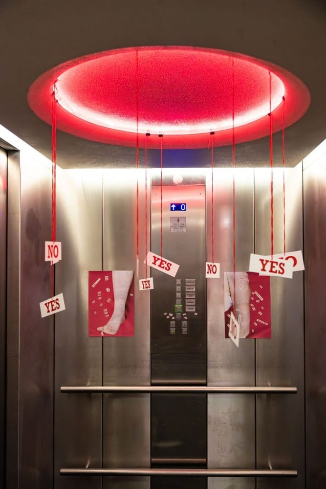 YES and NO signs hanging on red thread in a lift